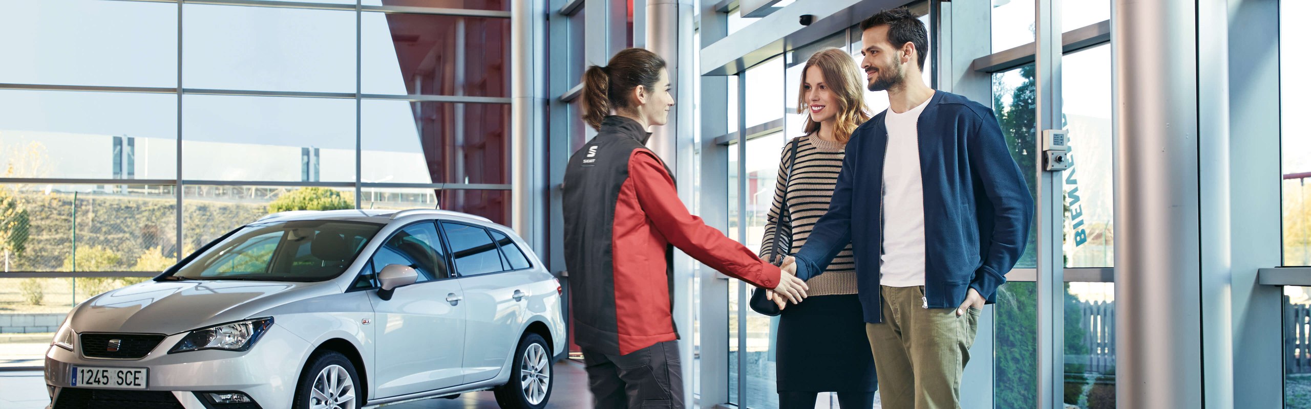 A couple shaking hands with a mechanic within a service centre