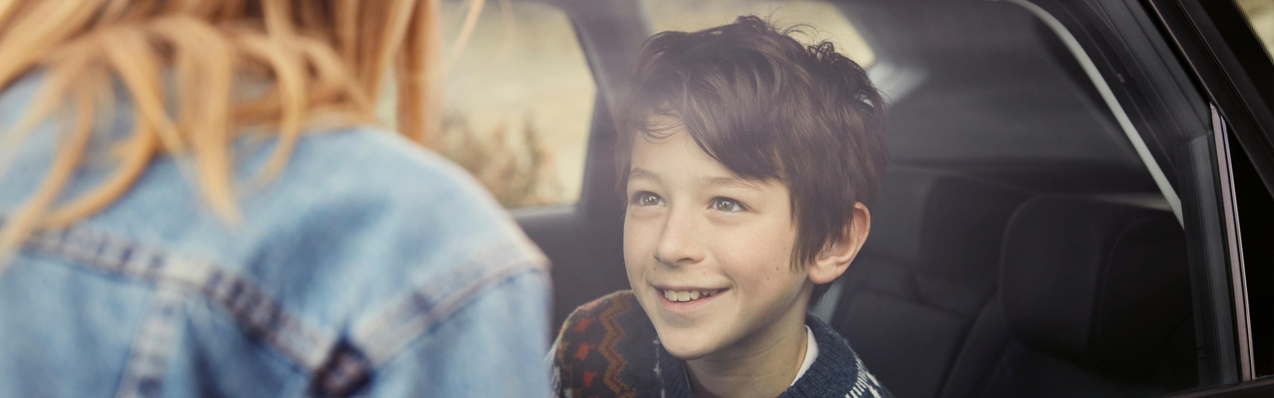 boy sitting on the back seat of a SEAT car looking at a woman