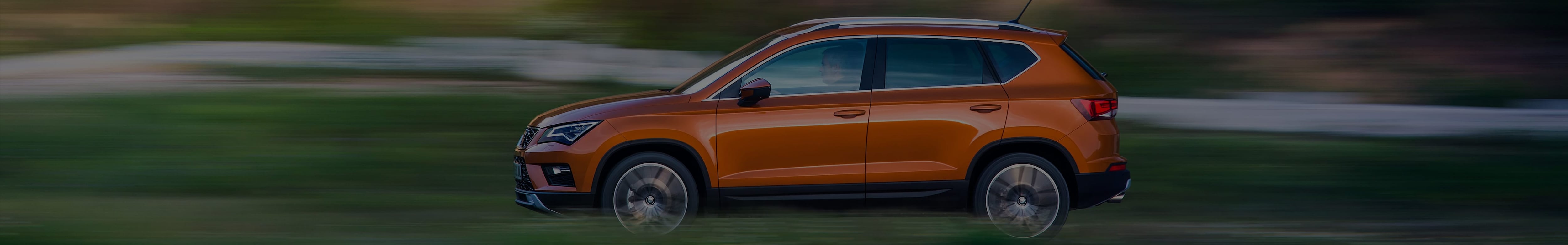 Side view of a brown SEAT driving in the countryside