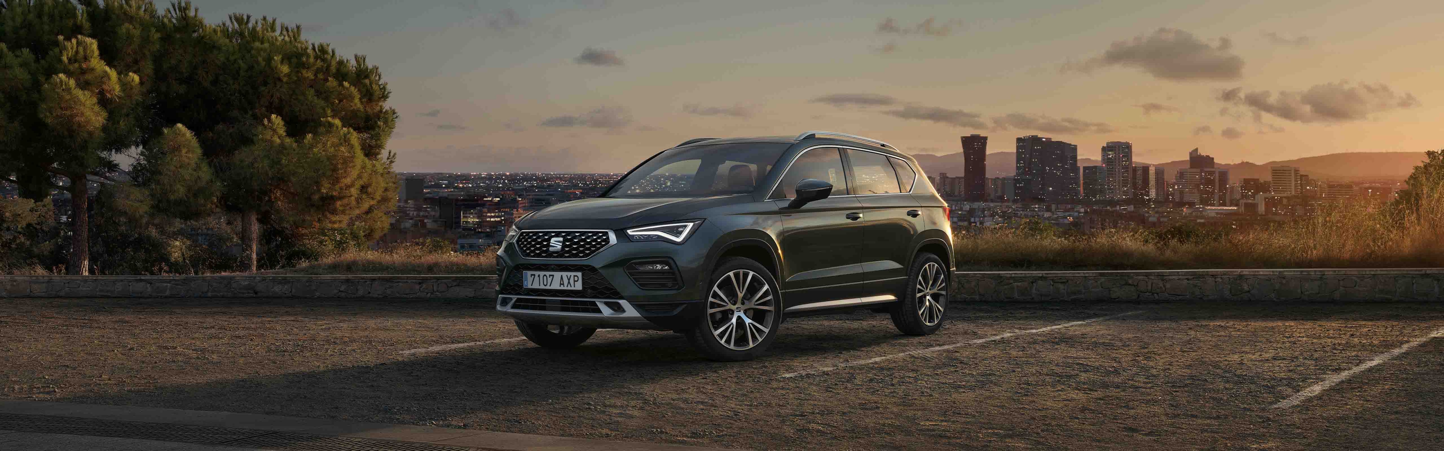 A black SEAT Ateca on top of a hill with  a city in the background below