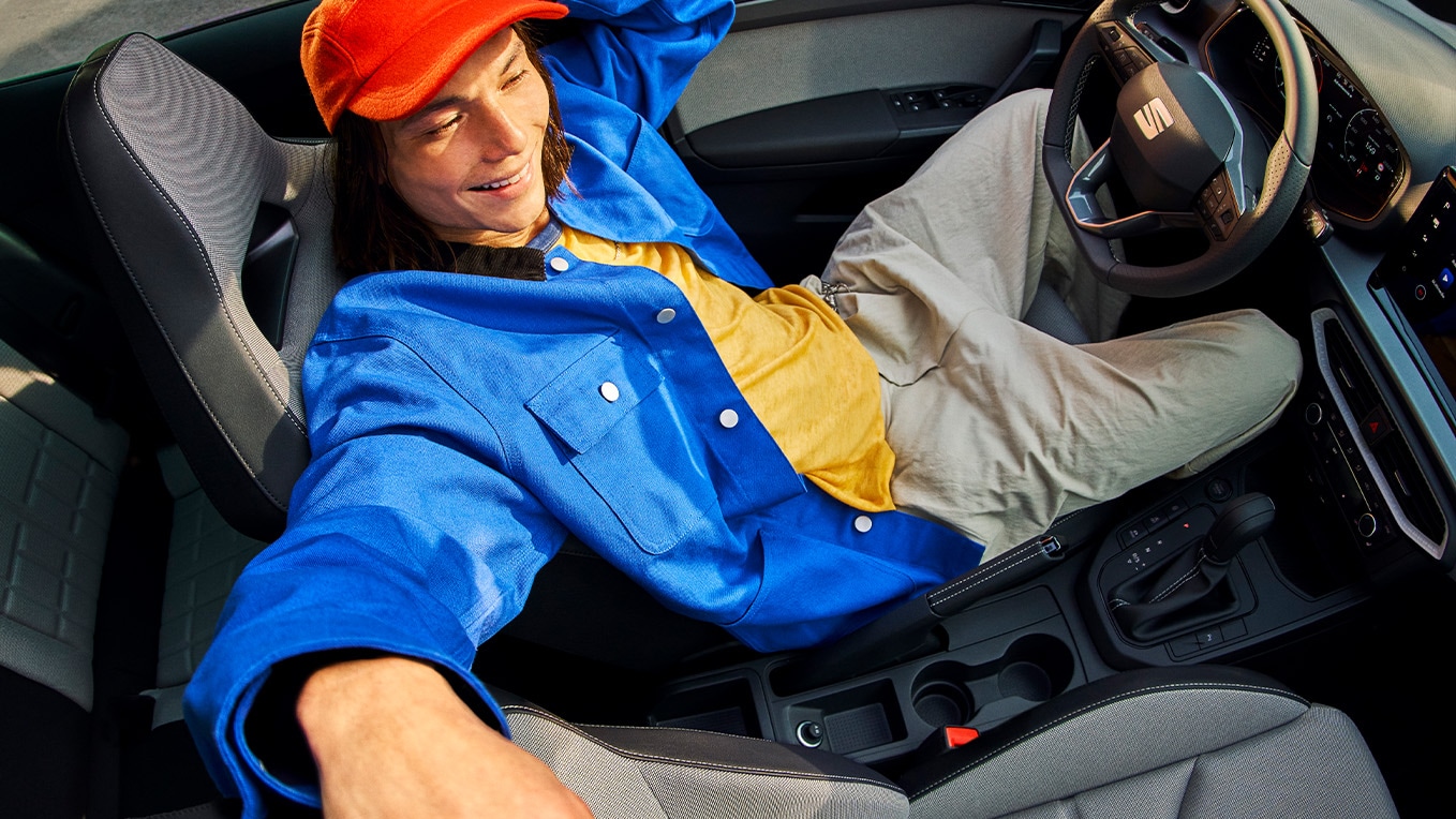 Interior of SEAT Ibiza showing modern dashboard, stylish seats and open sunroof with a person reclining inside the car