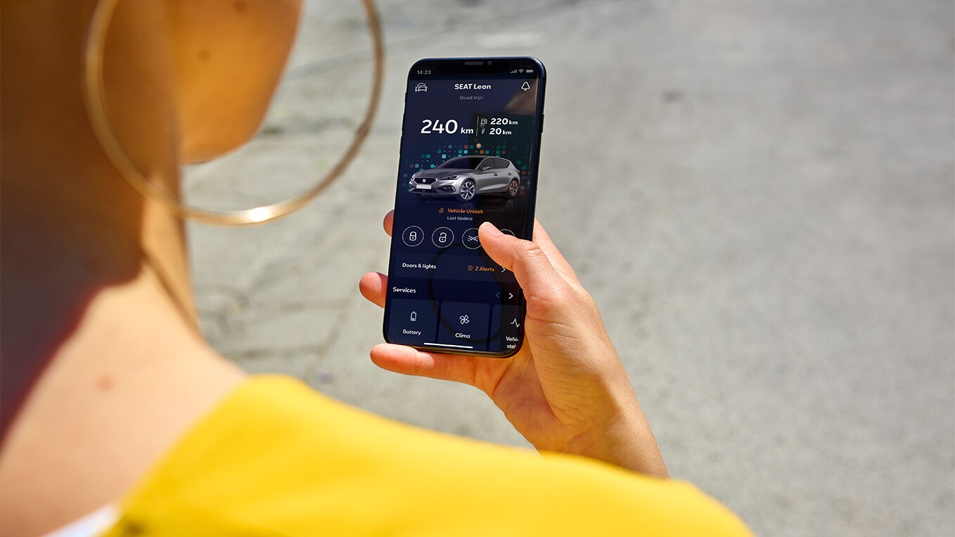 A person holding a mobile phone that is displaying the SEAT Connect app on the screen.