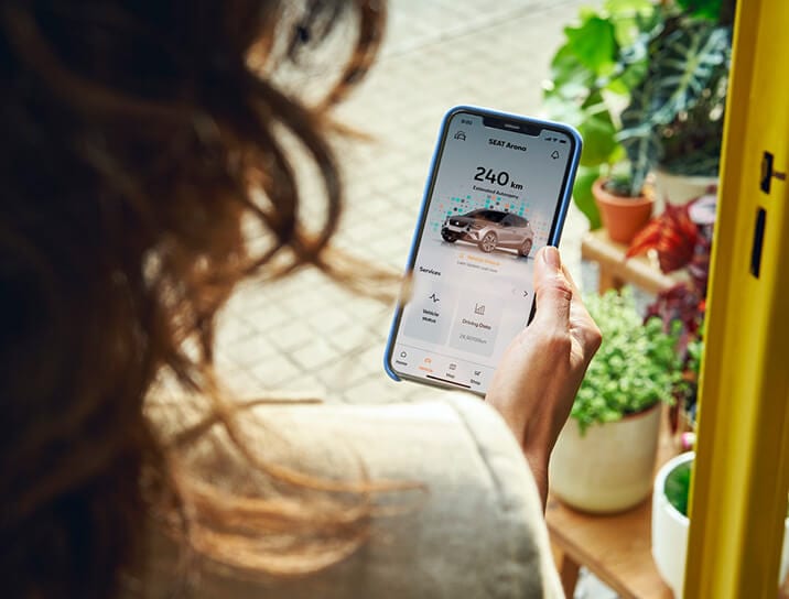 A woman looking at the SEAT Connect app on a smartphone