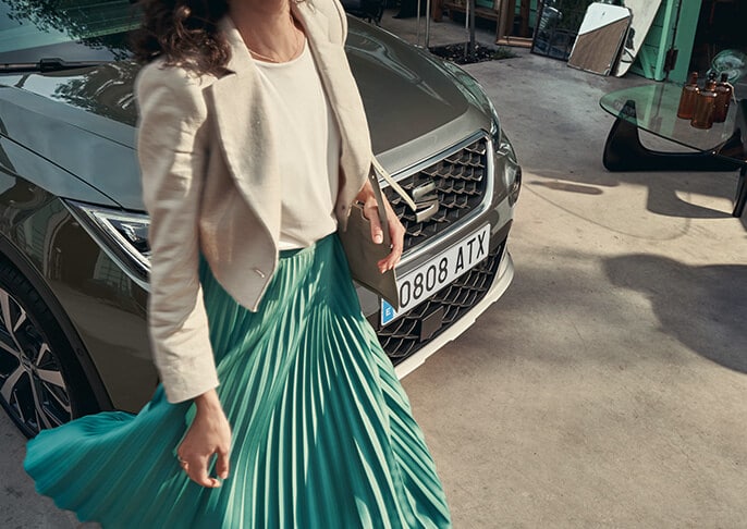 A woman walking beside a SEAT Arona XPERIENCE