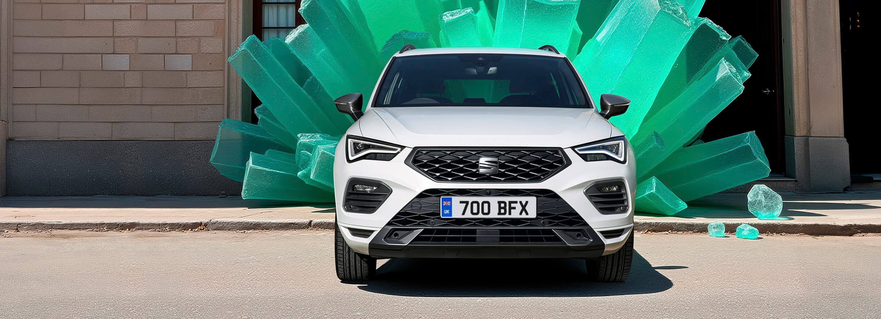 A front facing white SEAT Ateca with giant turquoise coloured plastic sticks in the background
