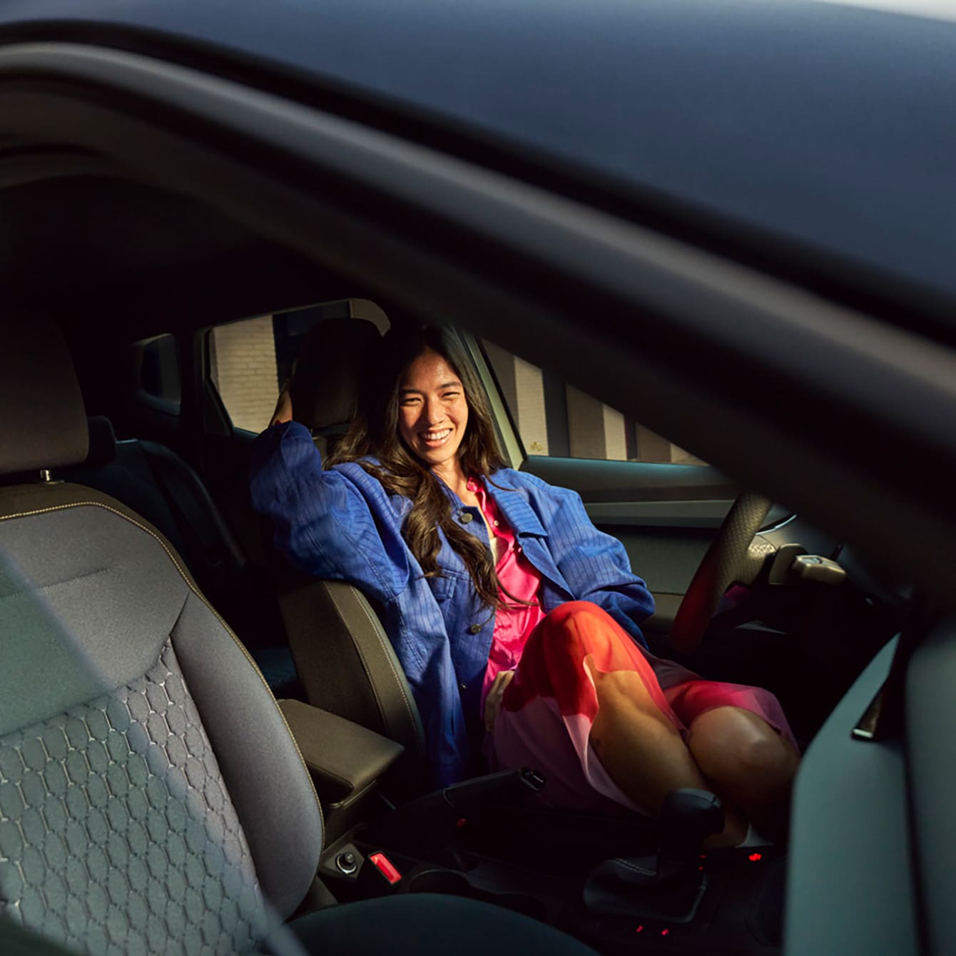 A smiling woman sat in the front seat of a SEAT car 
