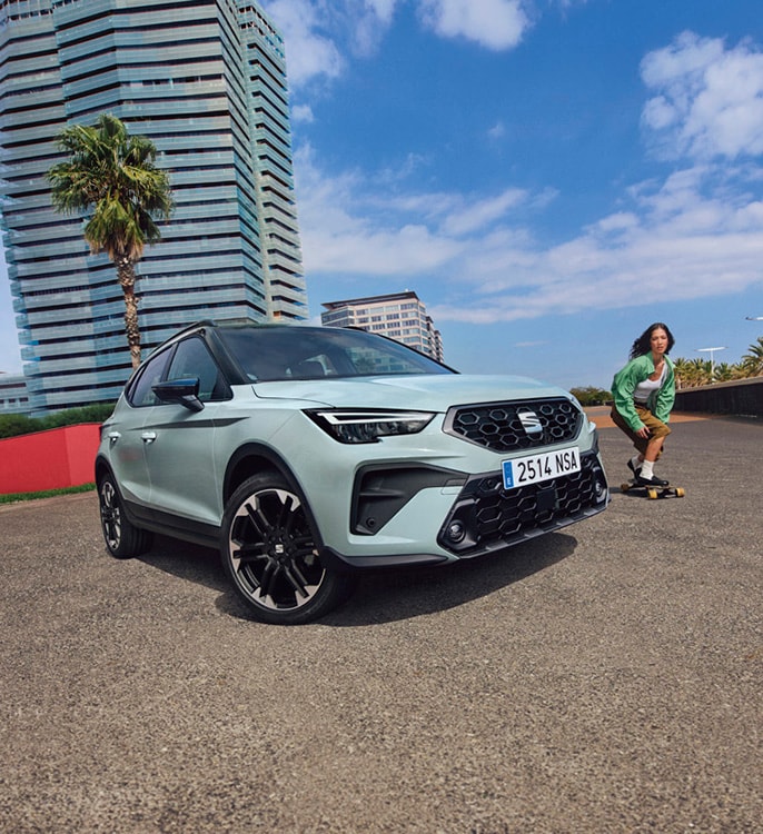 The back of a woman walking towards a red SEAT Ateca parked on the street