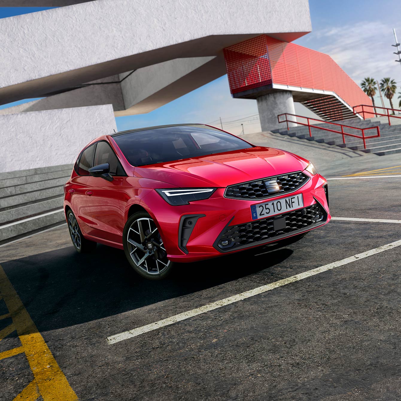 A red Ibiza parked in a car park next to a building