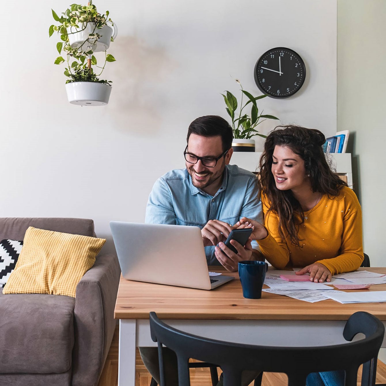 A couple sitting at a desk while looking at an open laptop