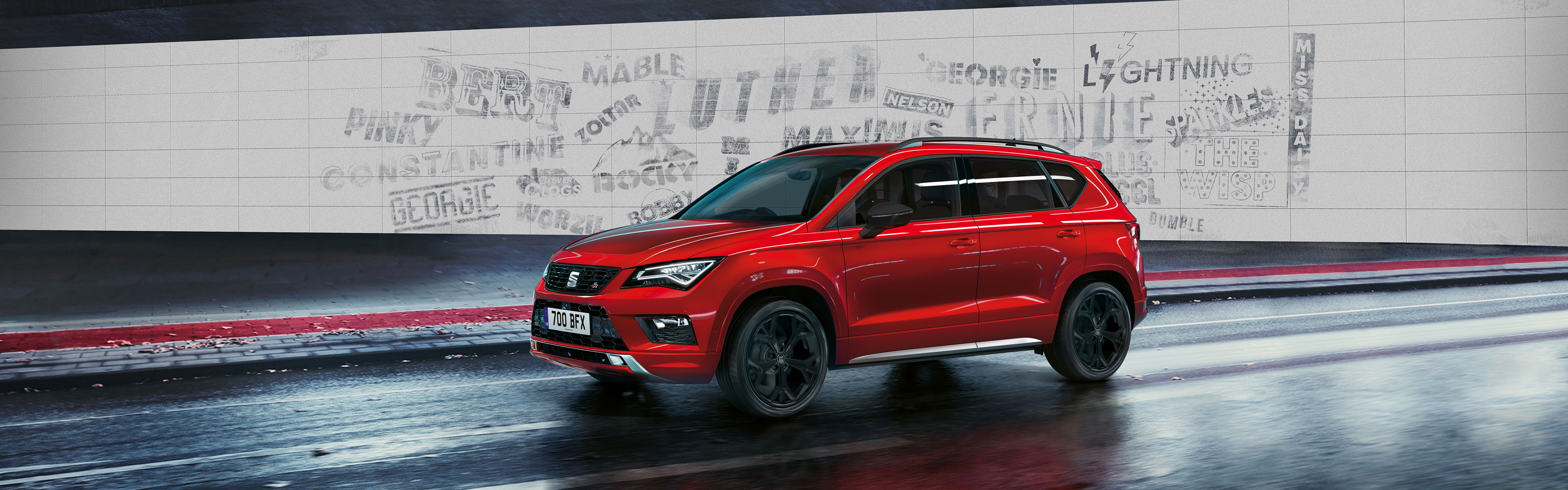 A first generation red SEAT Ateca with a grey wall in the background