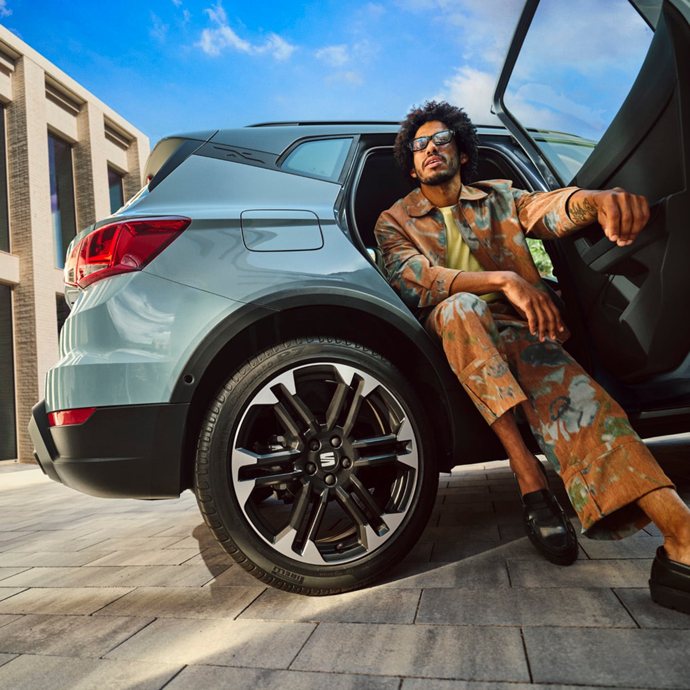 A man sitting in the back of a SEAT Arona facing outwards with the door open and his feet on the ground