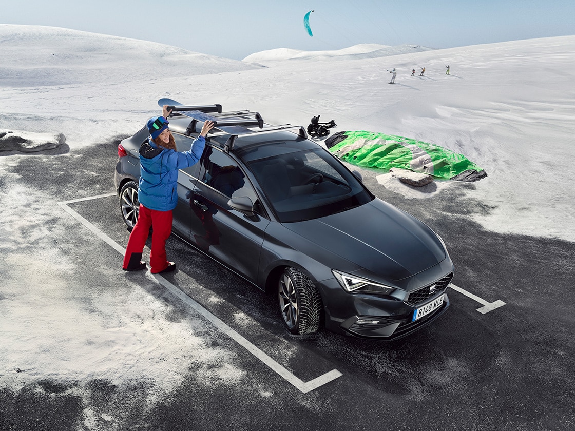 A red seat leon car parked on a mountain road waiting for seat service mobility and roadside assistance benefits. Two people standing nearby.