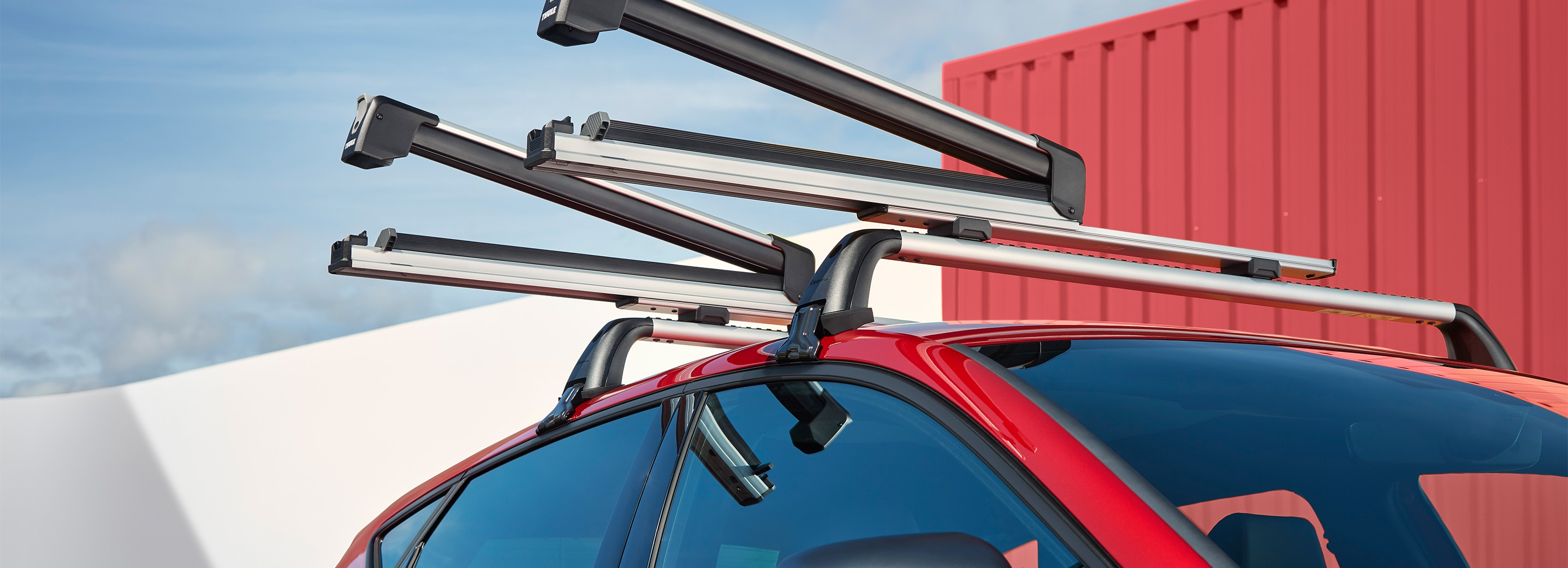 A red seat leon parked in an outdoors environment, showcasing the roof rack that secures several skis.