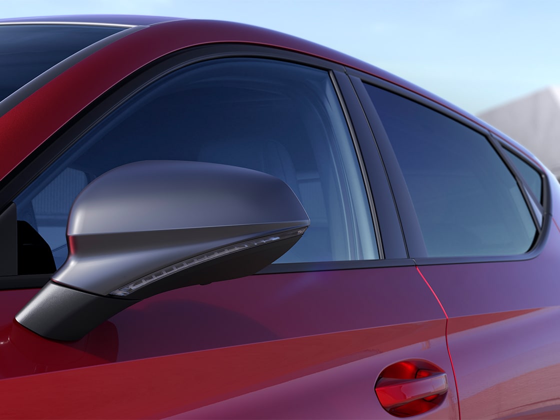 Side view of a SEAT Leon SP in red parked in a sunny, outdoors environment that highlights the exterior details of the FR Pack