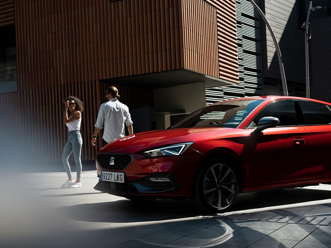 Red SEAT Leon in a sunny, outdoors setting to show that you have the possibility of stay safe and connected wherever you go, thanks to seat connect.